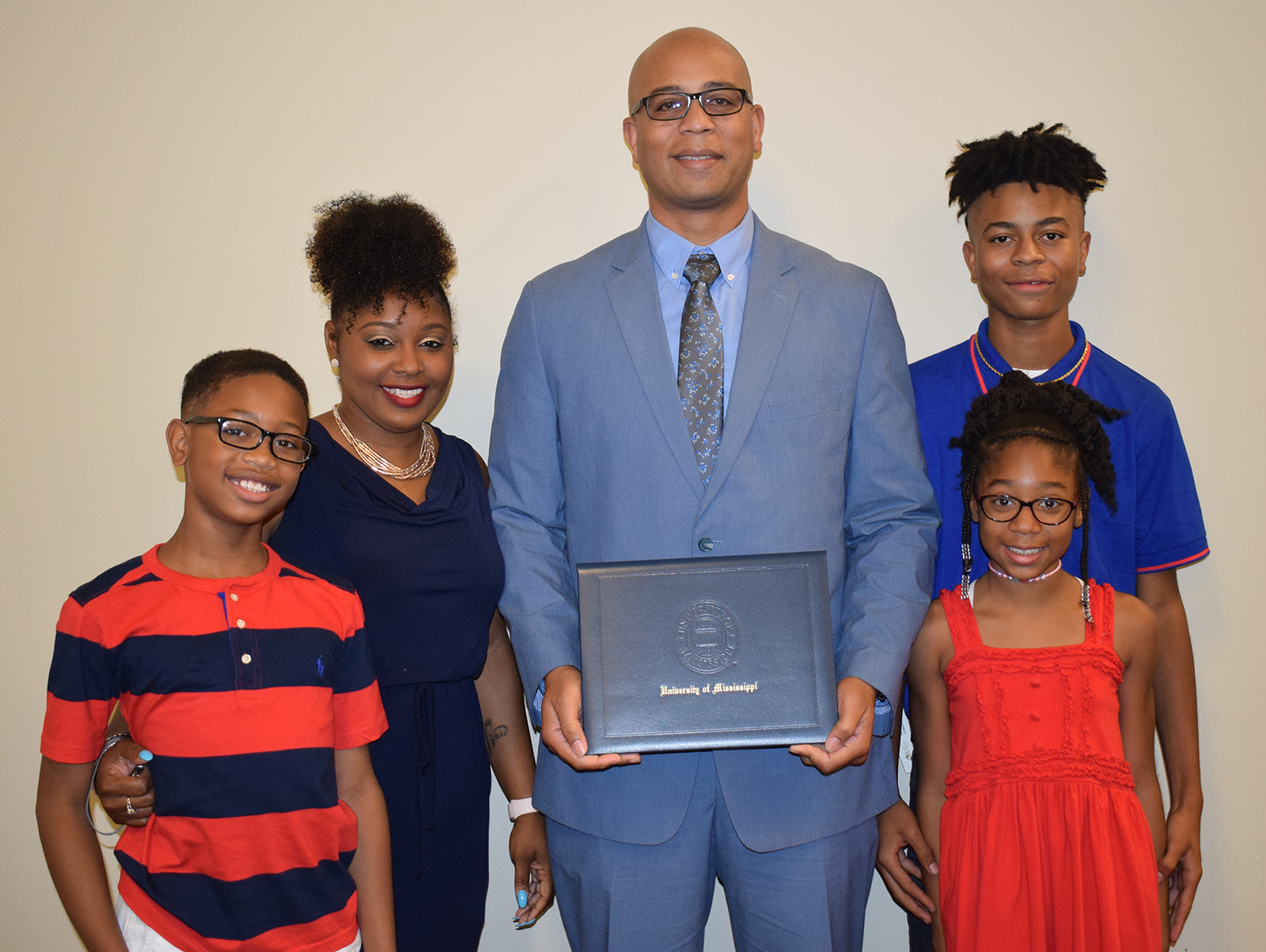 A Bachelor of University Studies graduate stands alongside his family at a ceremony honoring his accomplishments. 