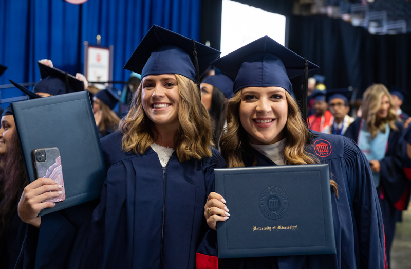 Two graduates from the Office of General Studies hold diplomas at commencement. 